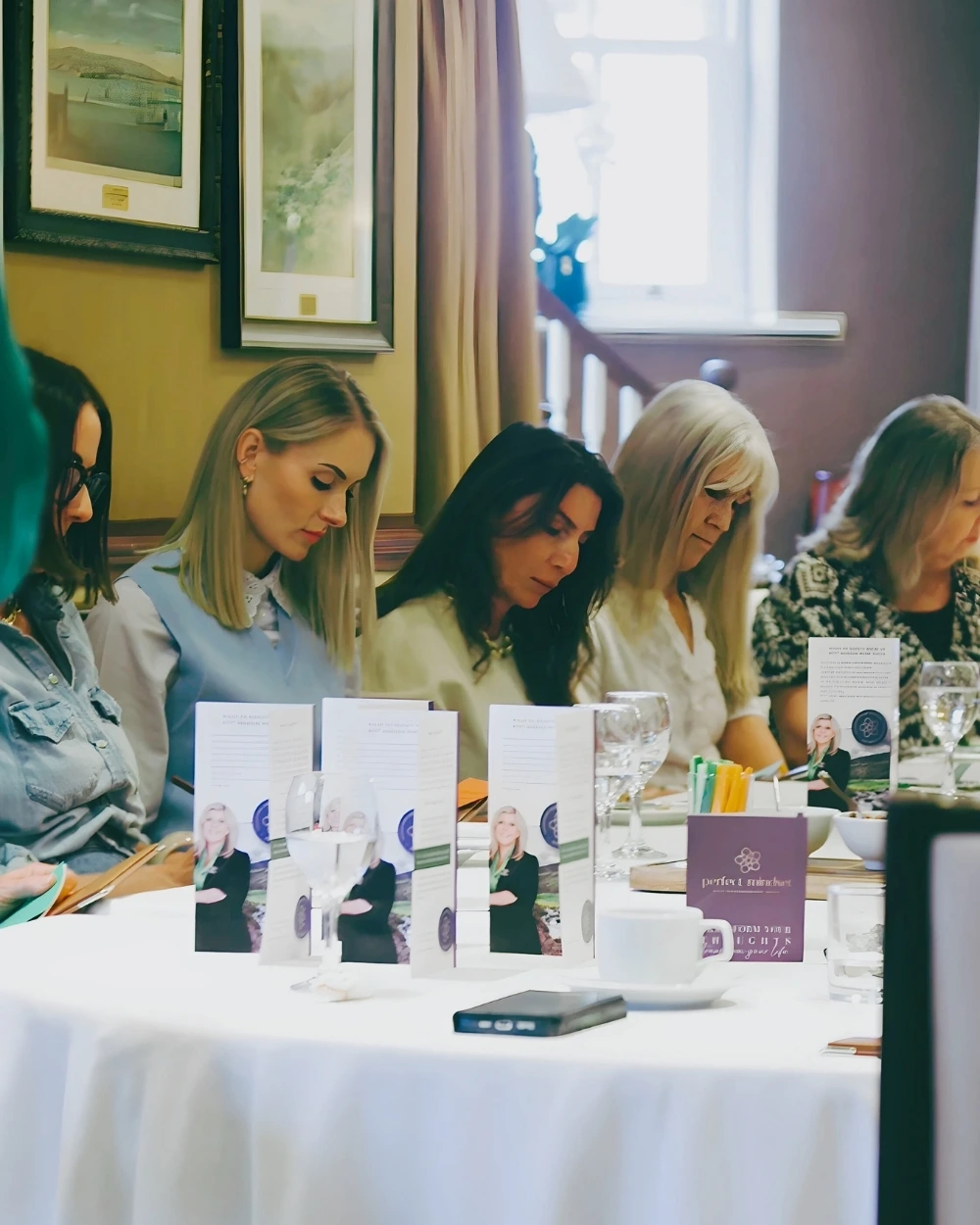 A group of women seated at a conference desk taking notes during an RTT workshop presented by Tanya Hames from Perfect Mindset